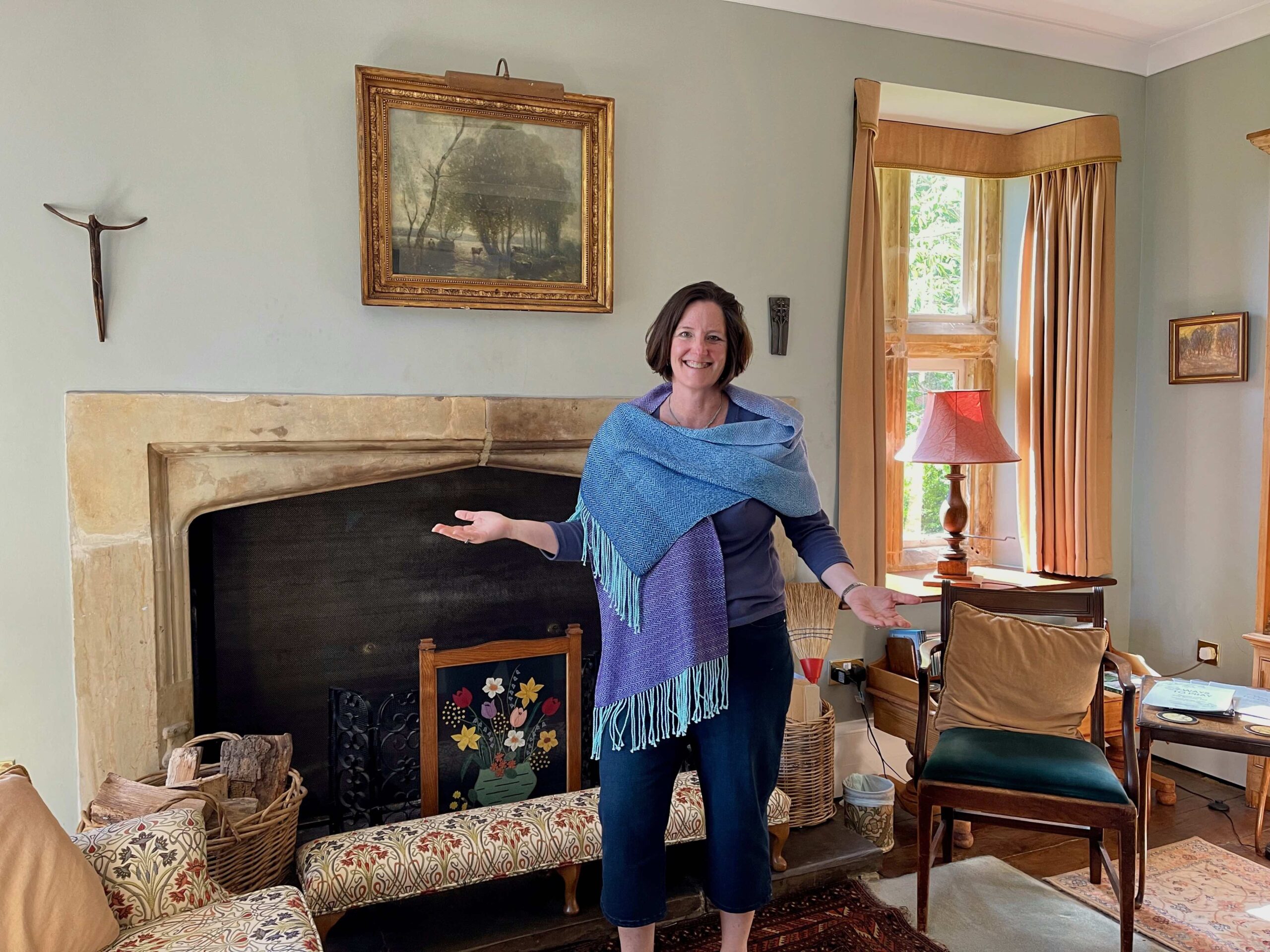 Amy in front of the fireplace at Penhurst Retreat Centre, wearing the beautiful blue and purple prayer shawl.